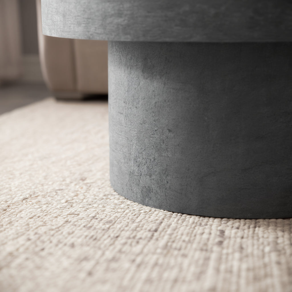 Detailaufnahme des runden Couchtischs in Stein-Optik mit Buch und Kerzen im modernen Stil _
