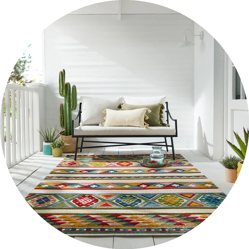 Bunter Outdoor-Teppich mit geometrischem Muster, perfekt für Balkone oder Terrassen, kombiniert mit moderner Gartenmöblierung im mediterranen Stil.