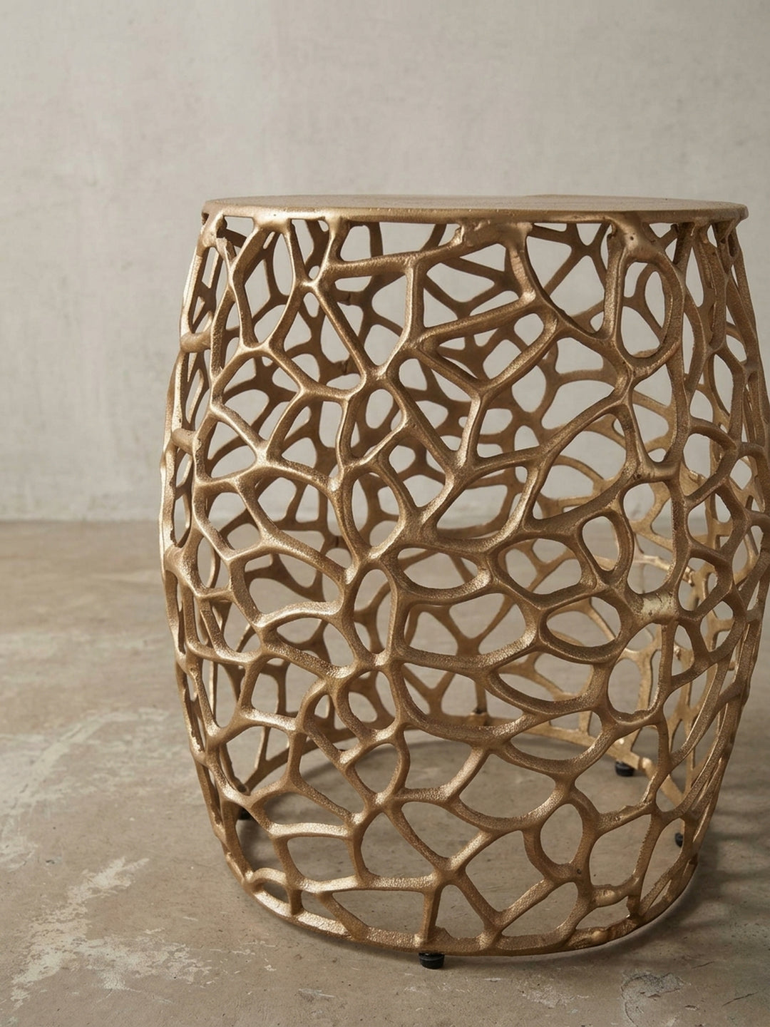 Detailaufnahme der Kante des goldenen Metalltisches, wo die glatte Tischplatte auf das organisch geformte Gestell trifft._