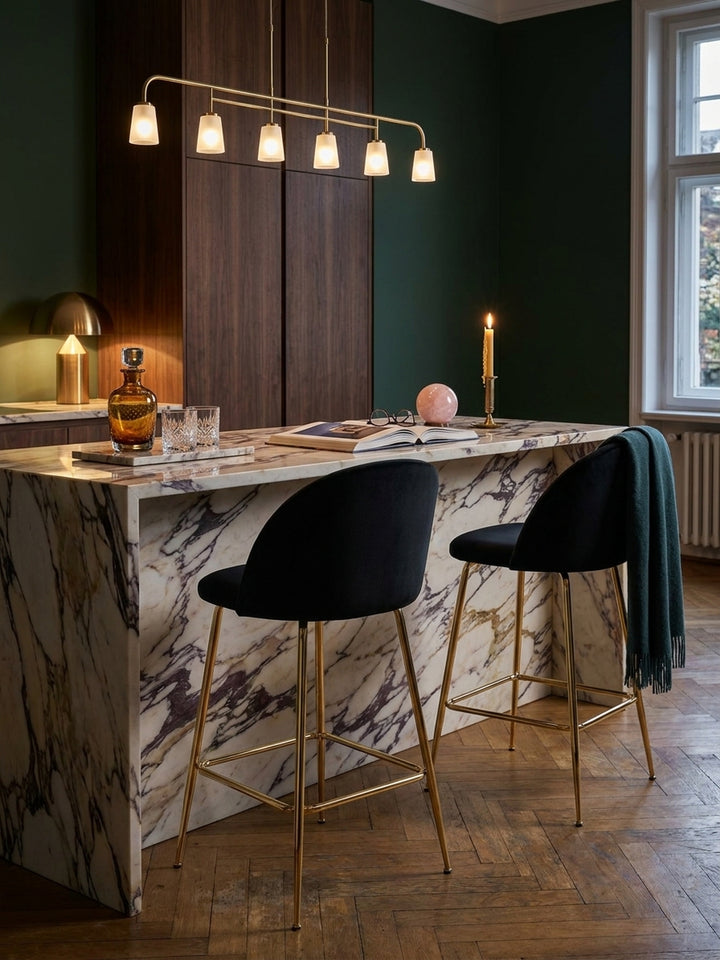 Schwarzer Barhocker mit Rückenlehne neben einem massiven Calacatta-Marmortablett mit Kristallgläsern unter einer filigranen Messingpendelleuchte_