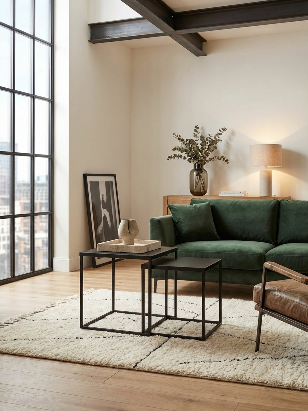Modernes Satztisch-Set aus schwarzem Metall im Wohnzimmer neben einem beigen Sofa, auf einem Teppich stilvoll mit Vase und Büchern dekoriert._