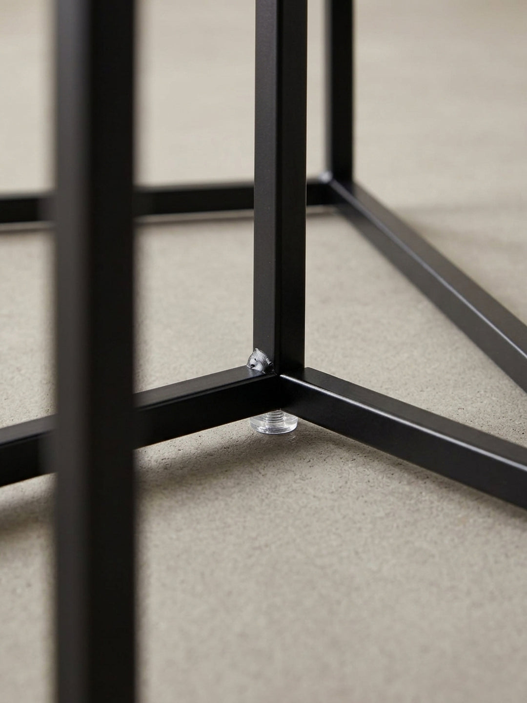 Nahaufnahme einer Ecke des schwarzen Couchtischs, die die saubere Kantenverarbeitung und die matte Lackierung des Stahlrahmens im Detail darstellt._