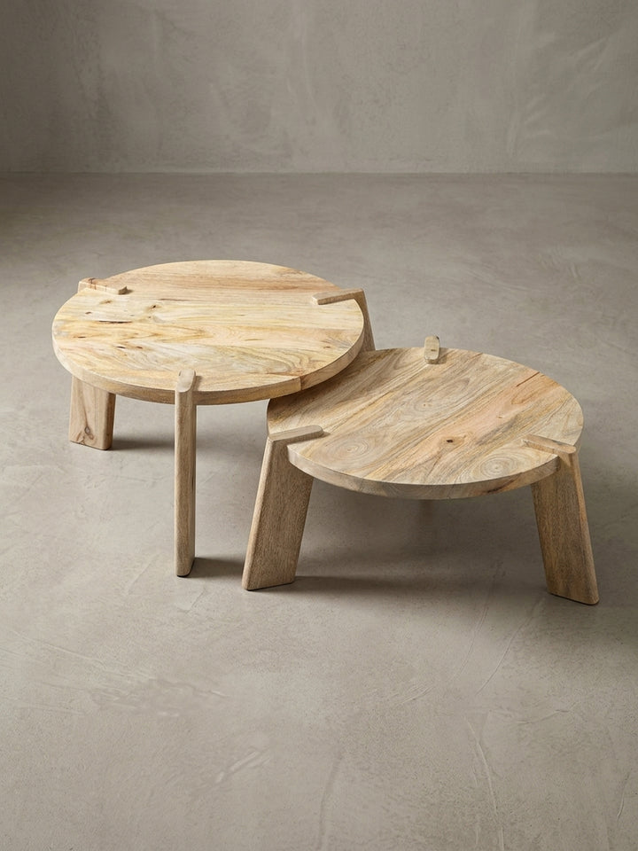 Nahaufnahme der durchgesteckten Tischbeine des runden Satztisches, ein charakteristisches Designmerkmal des Mango-Holztisches._