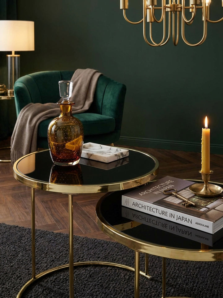 Kleiner Wohnzimmertisch aus Glas und Metall stilvoll dekoriert mit einer Teetasse und Notizbuch unter einer messingfarbenen Stehlampe_
