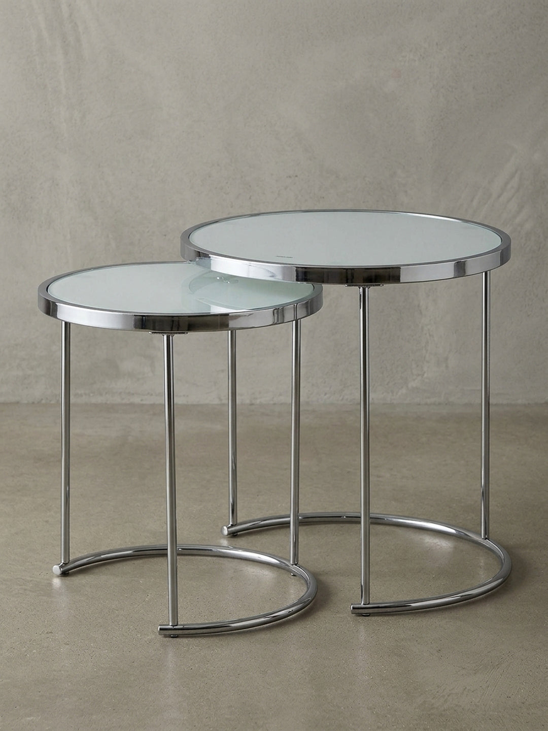 Überblick über den eleganten Satztisch aus weißem Glas und Chrom, dessen minimalistisches Design und runde Formen in jedes moderne Wohnzimmer passen._