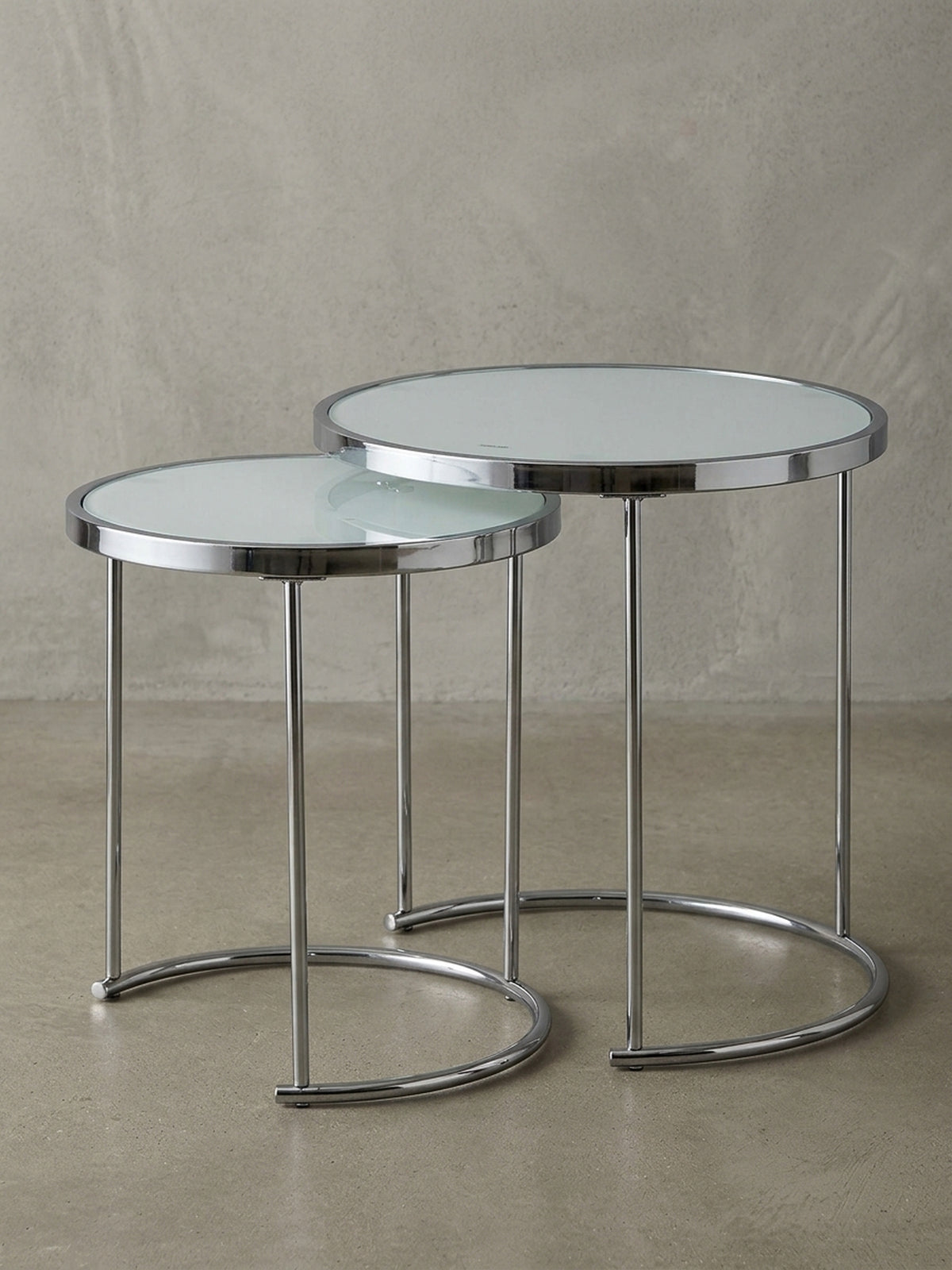 Überblick über den eleganten Satztisch aus weißem Glas und Chrom, dessen minimalistisches Design und runde Formen in jedes moderne Wohnzimmer passen.