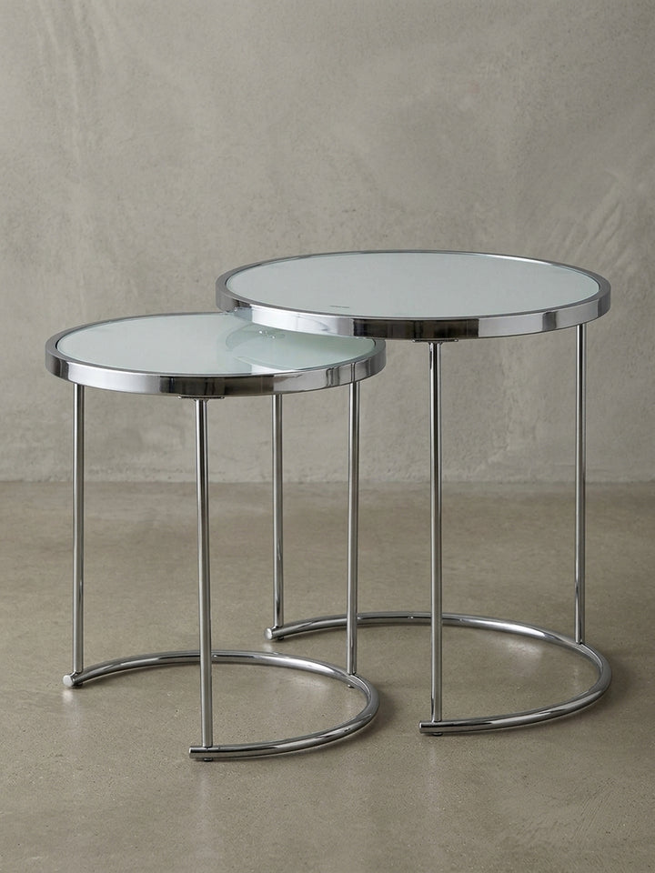 Überblick über den eleganten Satztisch aus weißem Glas und Chrom, dessen minimalistisches Design und runde Formen in jedes moderne Wohnzimmer passen._