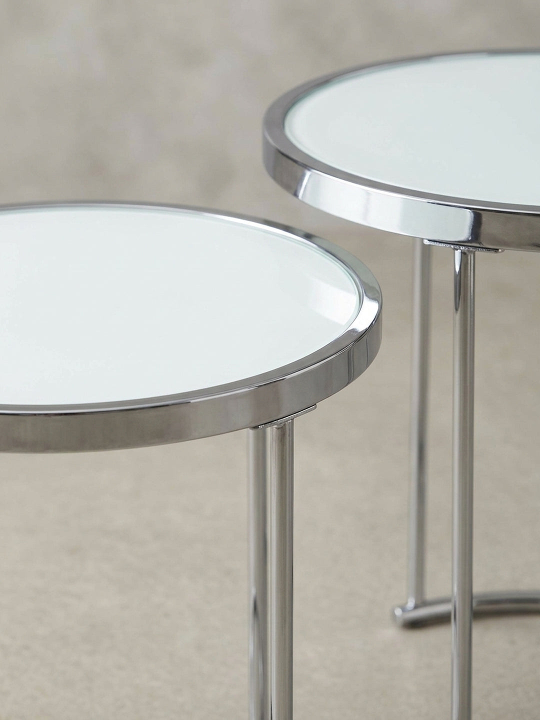 Nahaufnahme eines Details des verchromten Metallgestells des Beistelltisches, das die präzisen Verbindungen und die glänzende Oberfläche des modernen Designs hervorhebt._