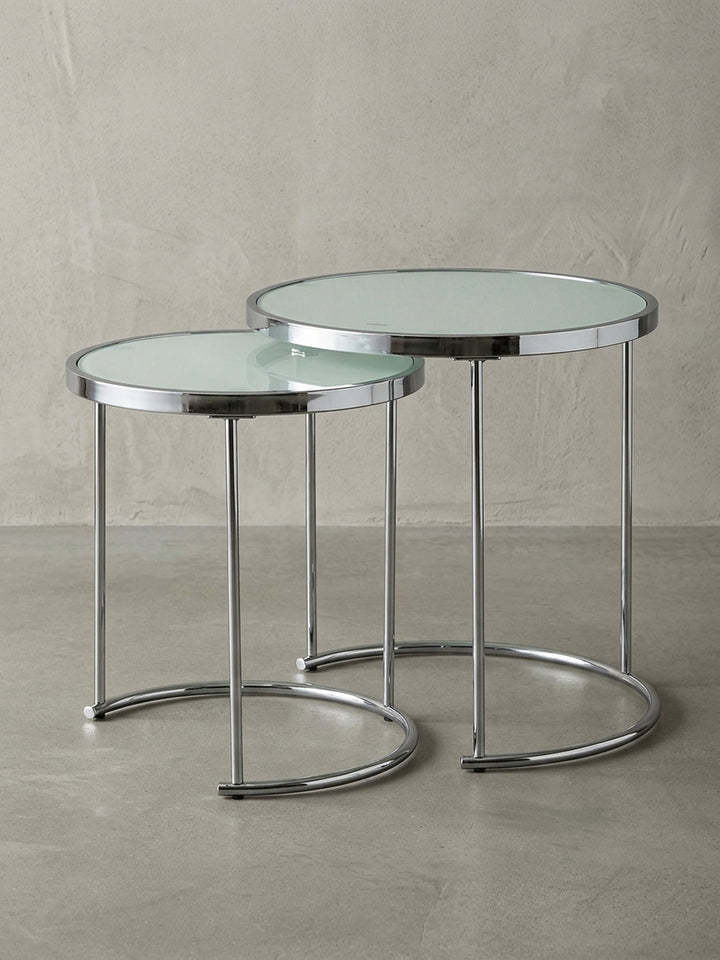 Runder Design Satztisch mit Gestell aus Chrom und weißer Glasplatte auf weißem Hintergrund, Frontalansicht des 2er Sets ineinander geschoben, Maße 50 und 42 cm Durchmesser._