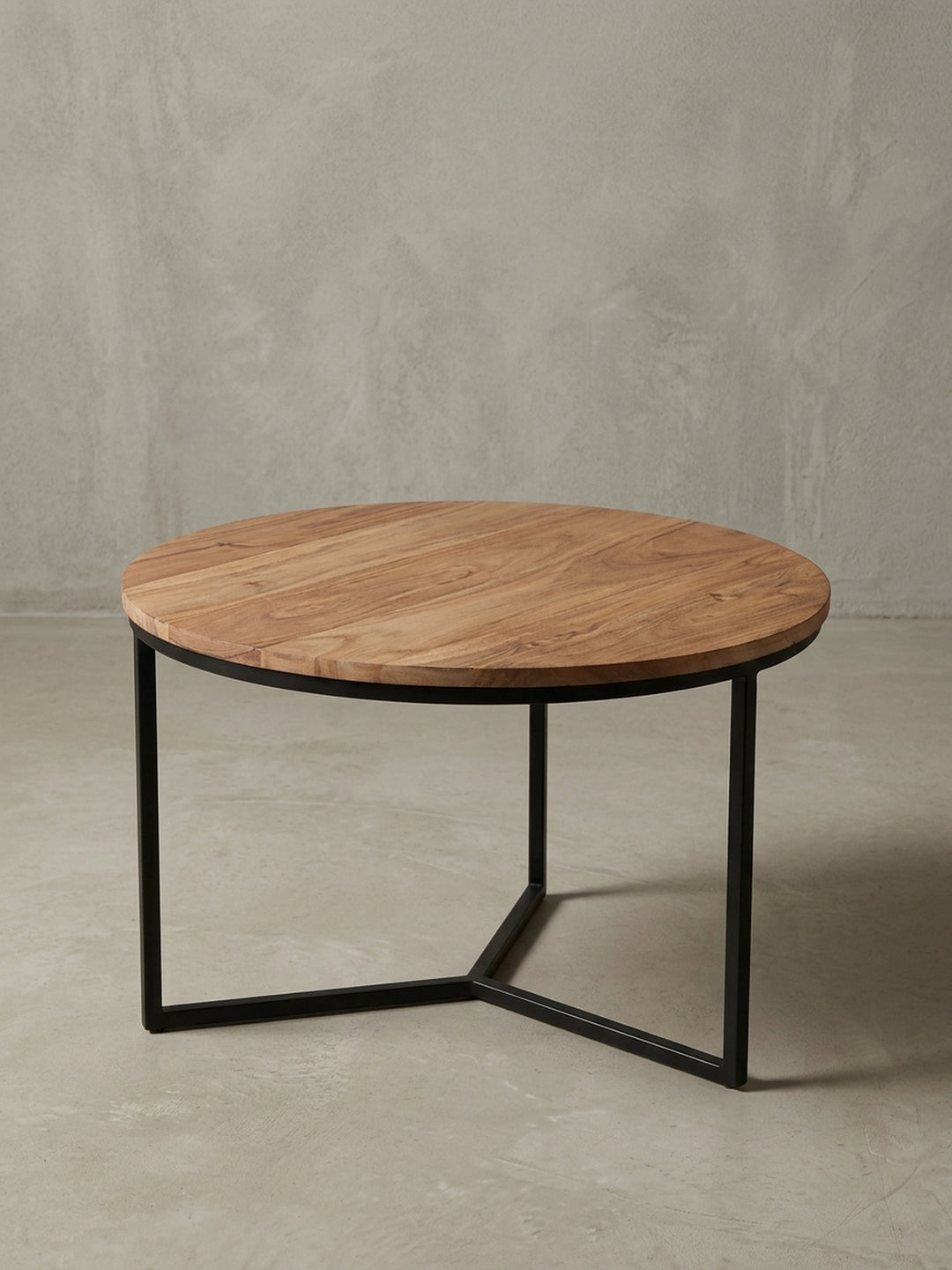 Design Couchtisch aus Akazie Massivholz in der 3/4-Ansicht, die die stabile Konstruktion des dreibeinigen Metallgestells hervorhebt und seine Form zeigt._