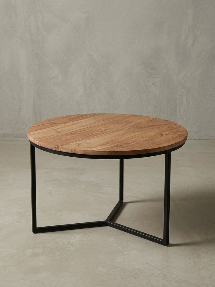 Design Couchtisch aus Akazie Massivholz in der 3/4-Ansicht, die die stabile Konstruktion des dreibeinigen Metallgestells hervorhebt und seine Form zeigt._
