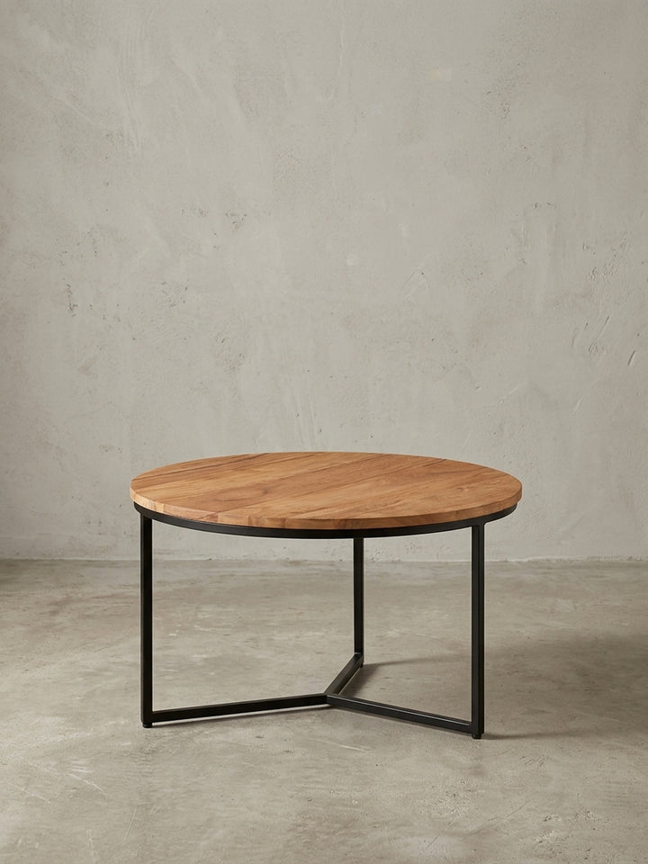 Freigestellter Couchtisch rund 60 cm, Frontansicht des Sofatisches mit warmer Akazienholzplatte und minimalistischem Gestell aus schwarzem Metall._