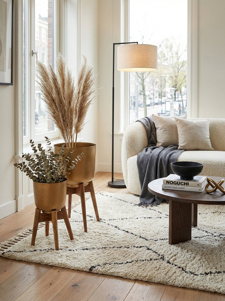 Modernes 2er Set goldener Blumentöpfe mit Massivholz-Beinen, elegant in einem hellen Wohnzimmer mit Trockenblumen arrangiert._