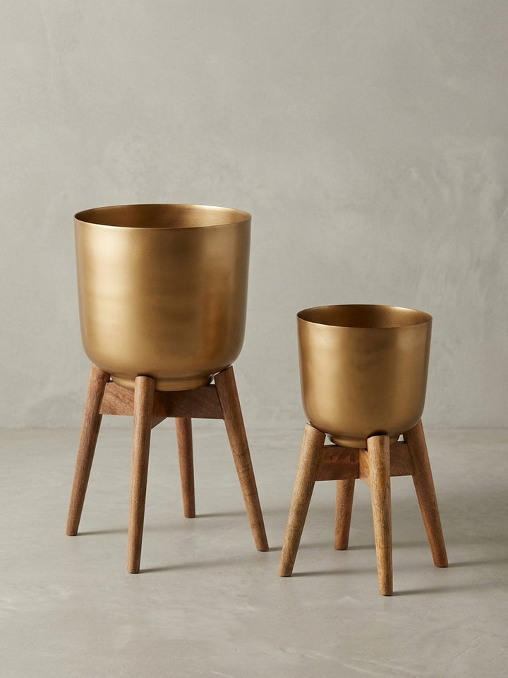 Dreiviertelansicht des großen Design-Pflanzkübels (52 cm hoch), der die schlanke Form der Holzbeine und die Proportionen zeigt._