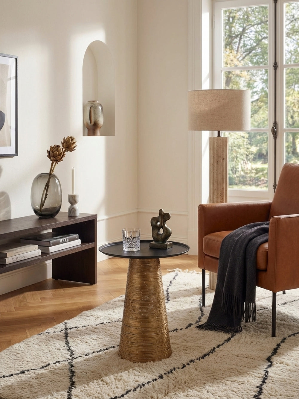 Runder Beistelltisch aus Metall von oben gesehen, mit schwarzer Tablett-Platte und goldenem Fuß, als eleganter Akzent im stilvollen Wohnbereich liebevoll arrangiert._