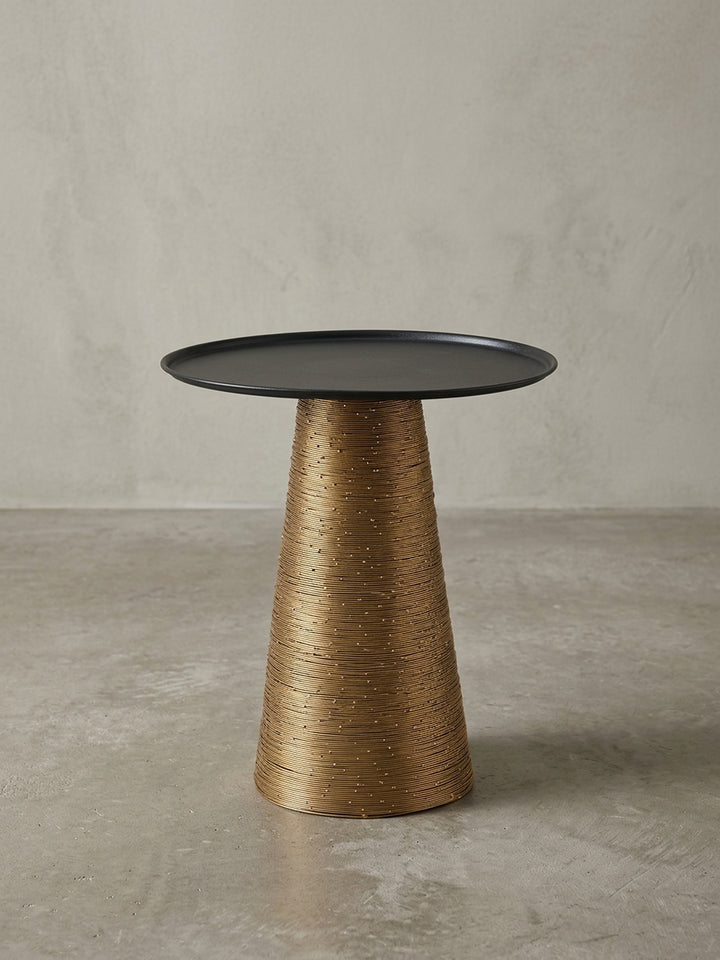 Seitenansicht des runden Couchtisches, der die Proportionen des 45 cm hohen Designs und die konische Form des kunstvoll gewickelten goldenen Standfußes klar hervorhebt._