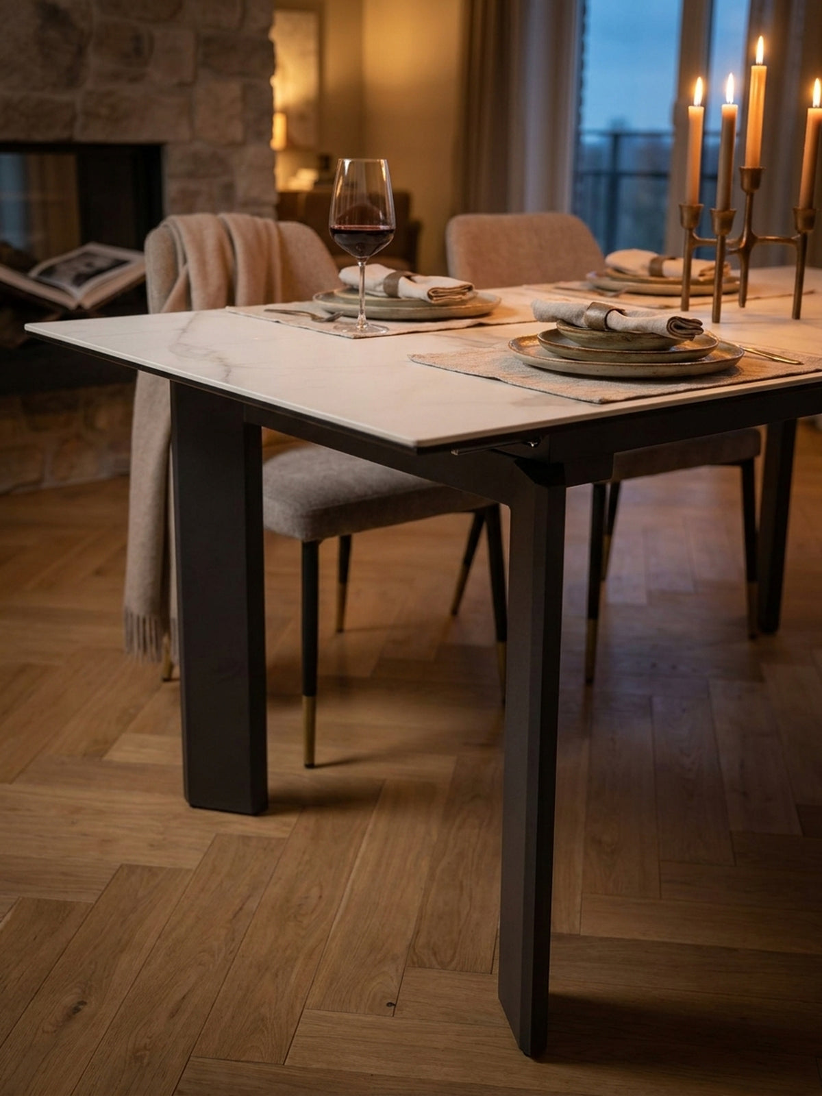 Detailaufnahme des weiß-marmorierten Esstisches mit einer schwarzen Vase und zwei Weingläsern, bereit für ein Abendessen.
