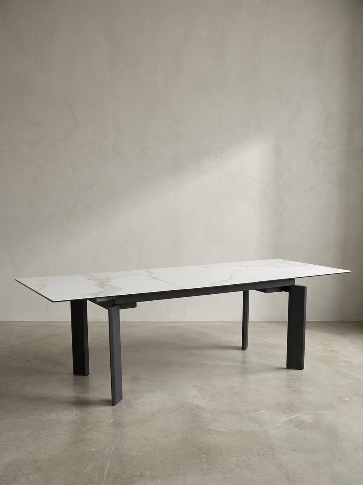 Gesamtansicht des Design-Esstisches, der die klaren Linien und den Materialkontrast von Keramik und pulverbeschichtetem Eisen verdeutlicht._