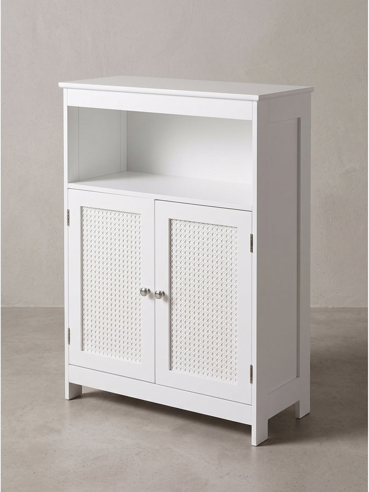 Makroaufnahme der perfekten Kantenverarbeitung des weißen MDF-Holzes und der fein geflochtenen Rattan-Einsätze am eleganten Badezimmerschrank._