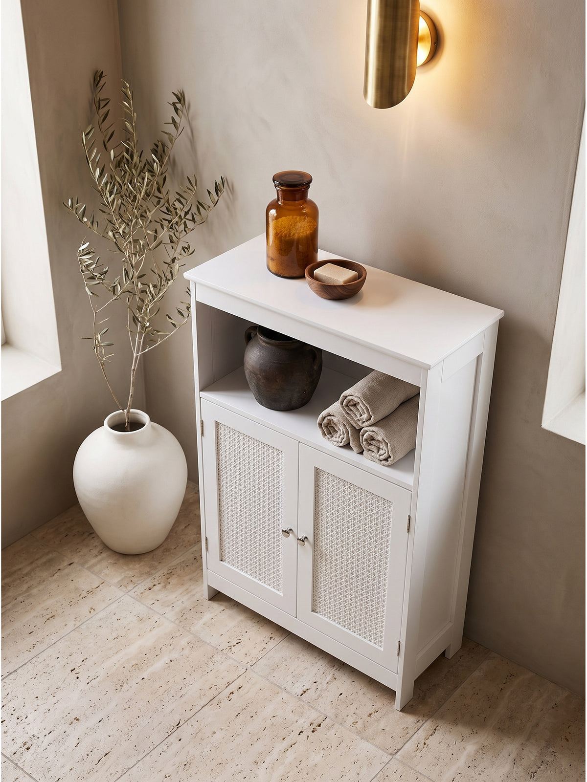 Draufsicht auf den weißen Badezimmerschrank mit natürlichen Rattan-Details arrangiert im minimalistischen Bad neben einer freistehenden Keramik-Badewanne._