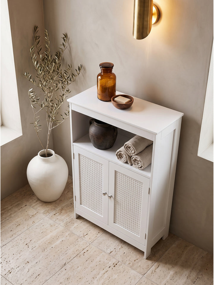 Draufsicht auf den weißen Badezimmerschrank mit natürlichen Rattan-Details arrangiert im minimalistischen Bad neben einer freistehenden Keramik-Badewanne._