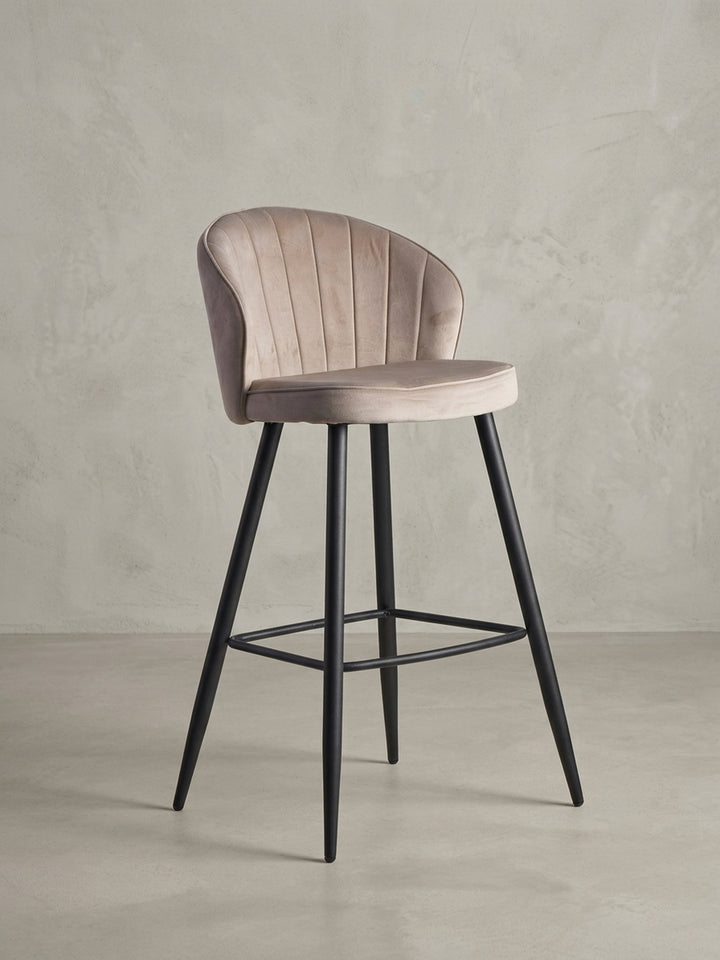 Barhocker in Beige Samt mit schwarzen Metallbeinen, Frontansicht auf weißem Hintergrund, zeigt die symmetrische Silhouette und Steppung._