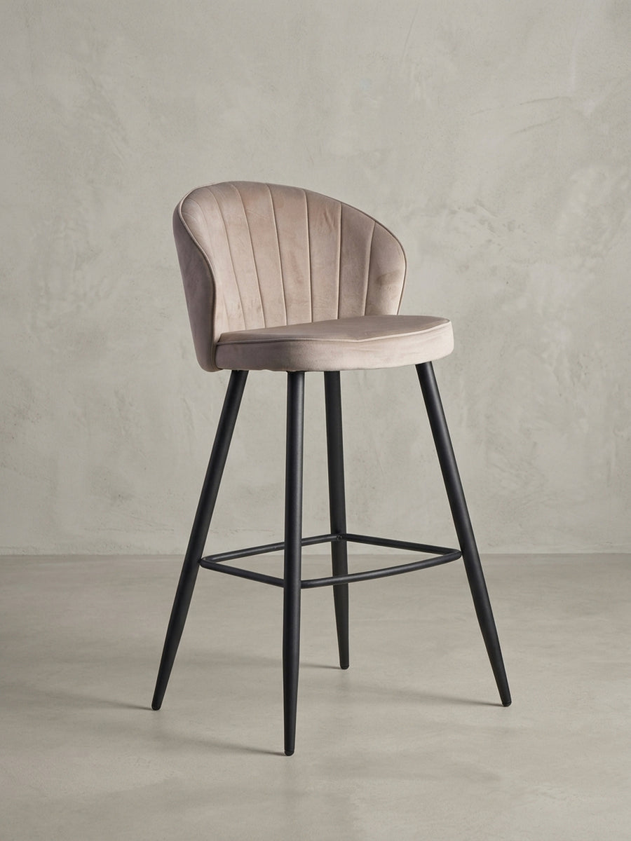 Barhocker in Beige Samt mit schwarzen Metallbeinen, Frontansicht auf weißem Hintergrund, zeigt die symmetrische Silhouette und Steppung._