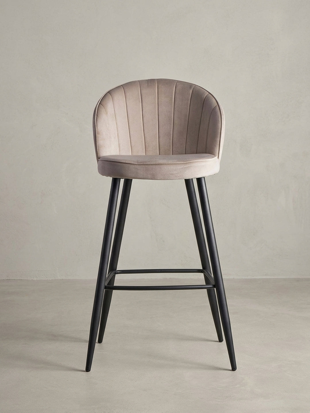 Skandinavischer Barhocker aus Samt in Beige, 3/4-Ansicht, die die geschwungene Rückenlehne und die stabile Konstruktion des Hockers betont._