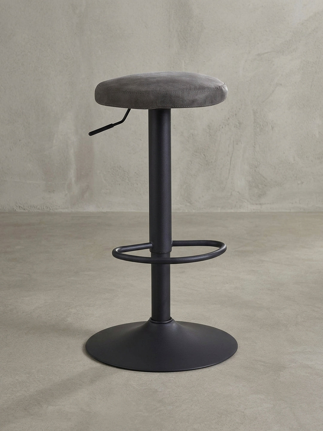 Design-Barhocker in 3/4-Ansicht, der die runde Sitzfläche aus grauem Stoff und den schlanken, höhenverstellbaren Standfuß aus mattschwarzem Metall hervorhebt._