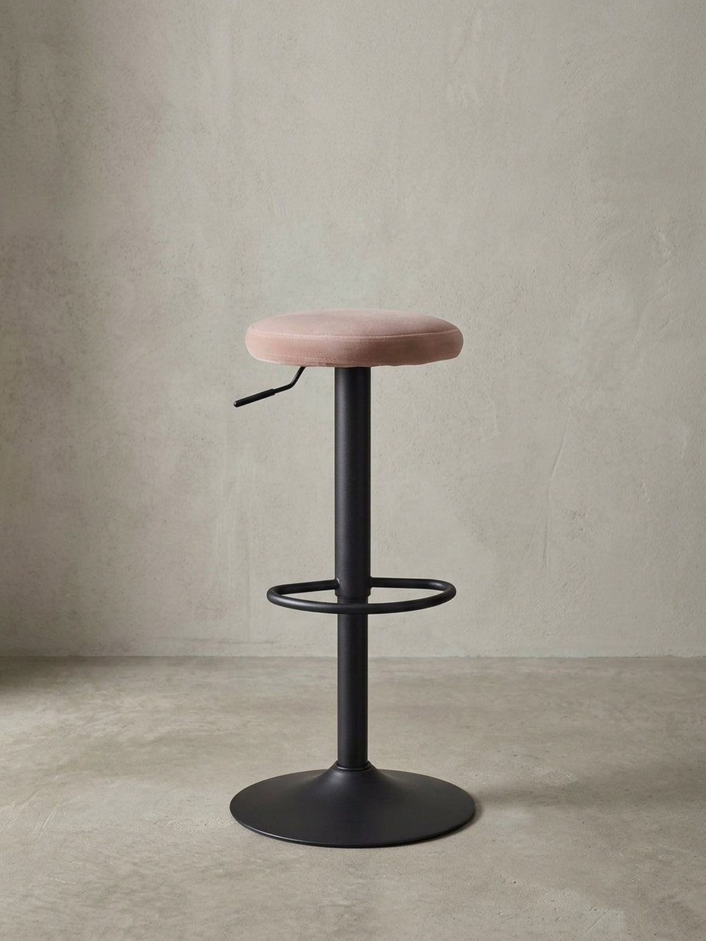 Studioaufnahme des Barhockers mit rosa Samtsitz und schwarzem Metallfuß, der die klare Silhouette und das moderne Design hervorhebt._