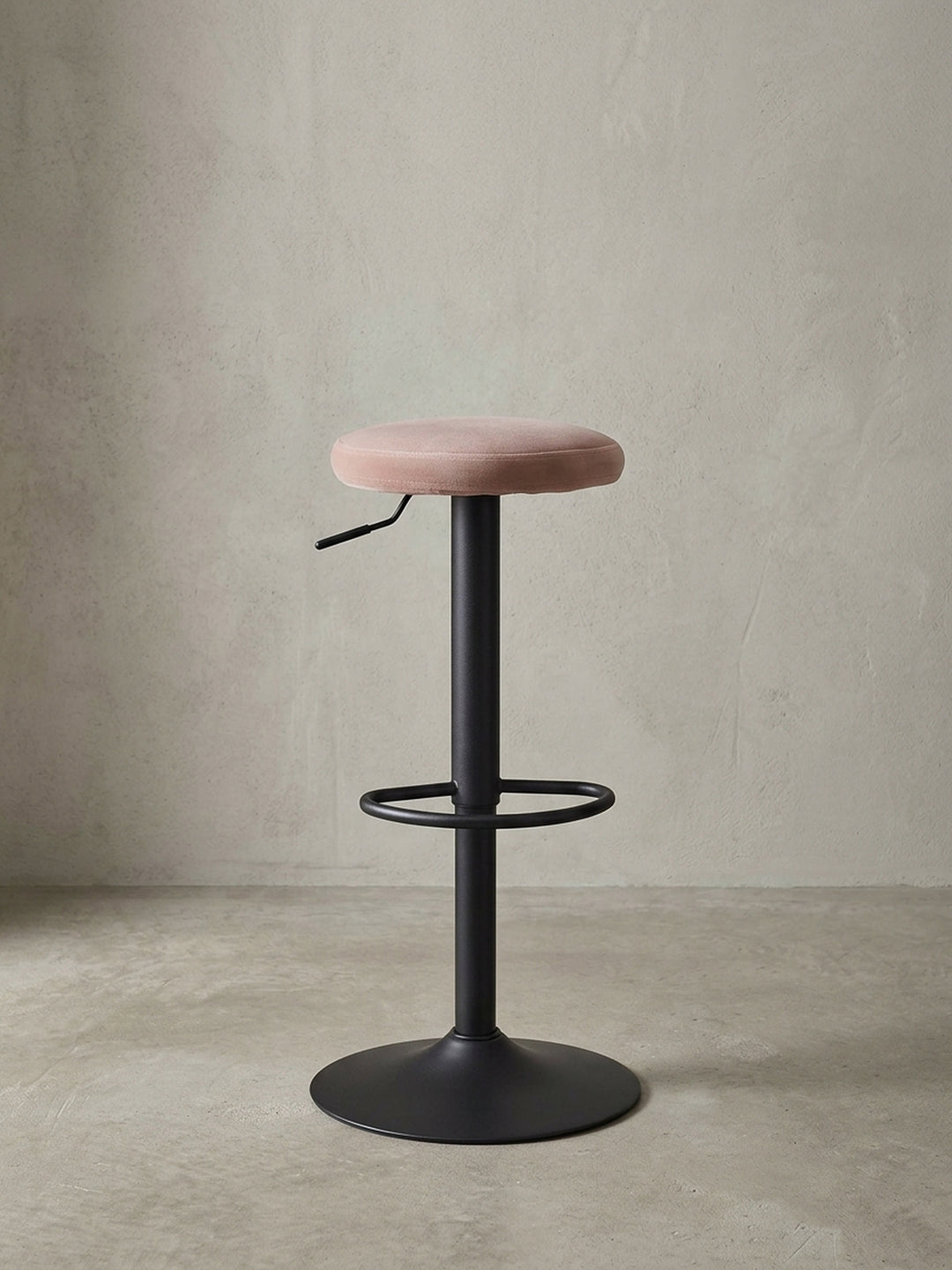 Studioaufnahme des Barhockers mit rosa Samtsitz und schwarzem Metallfuß, der die klare Silhouette und das moderne Design hervorhebt._