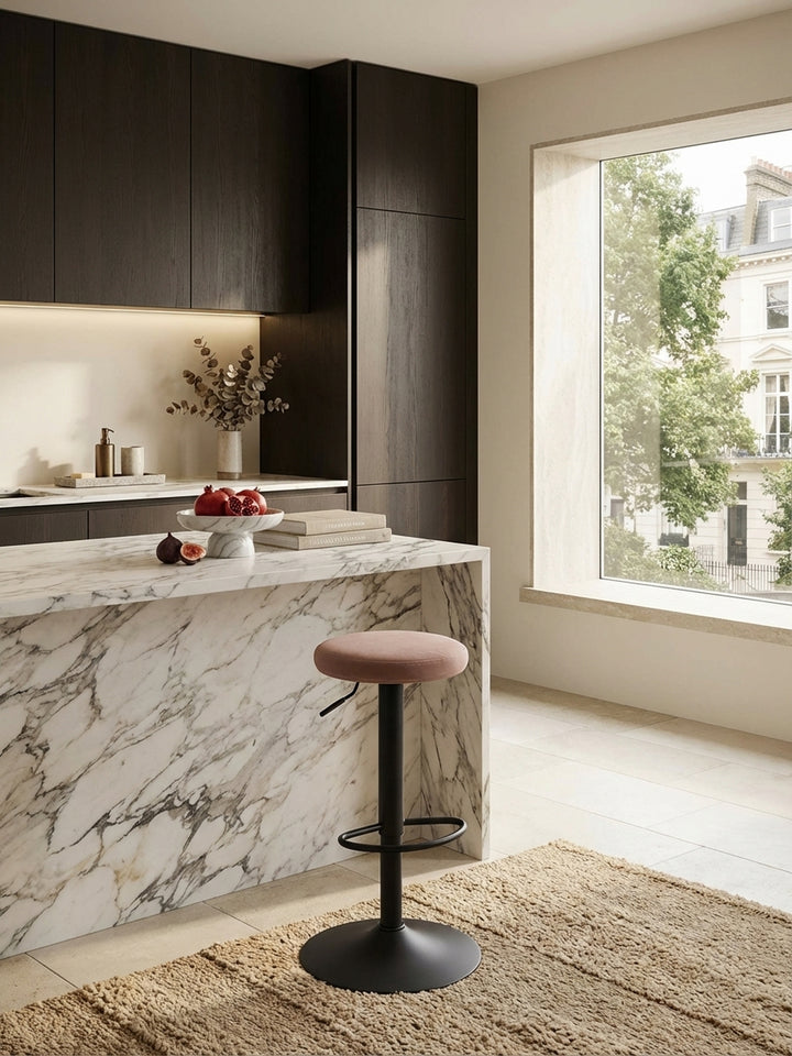 Design Barhocker aus Samt in Rosa an einer modernen Kücheninsel aus Marmor, stilvoll in Szene gesetzt in einer hellen, luxuriösen Küche._