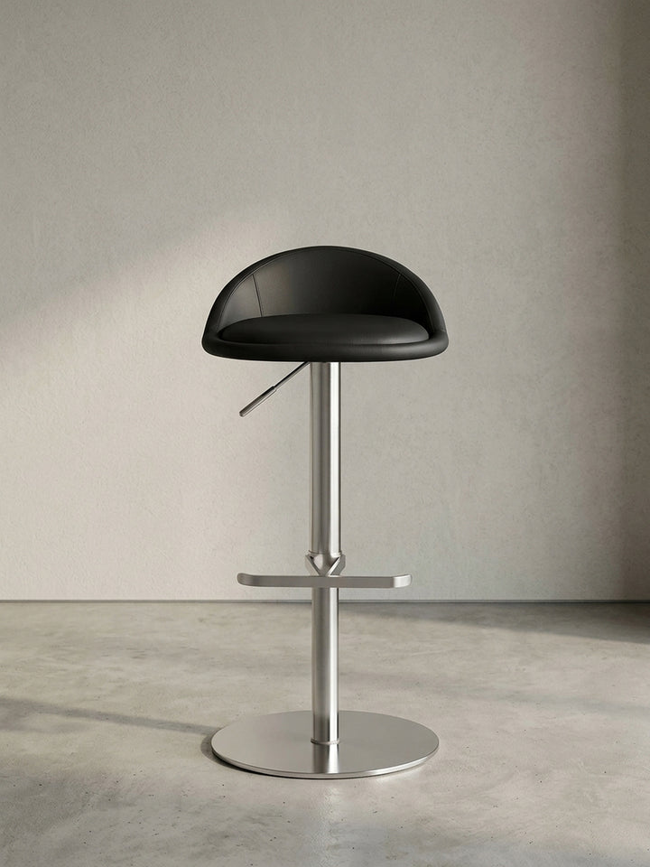 Schrägansicht des modernen Tresenhockers in Schwarz, die ergonomisch geschwungene Rückenlehne und die formschöne T-Fußstütze zeigend._