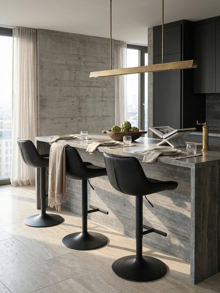 Zwei höhenverstellbare Barhocker aus schwarzem Kunstleder, elegant kombiniert mit einer dunklen Holzkücheninsel und Messing-Hängelampen._