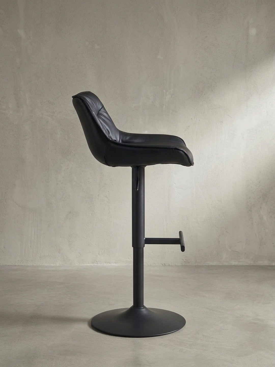 Seitenansicht des schwarzen Barhockers, die sein schlankes Profil und die ergonomische Höhe der Fußstütze verdeutlicht._