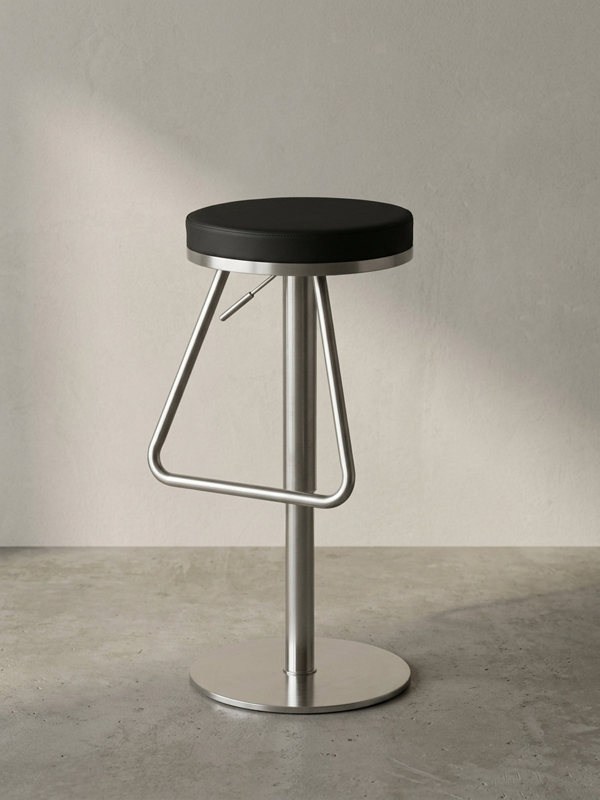 Dreiviertelansicht des modernen Thekenhockers, welche die elegante dreieckige Fußablage und den stufenlos höhenverstellbaren Metallzylinder betont.