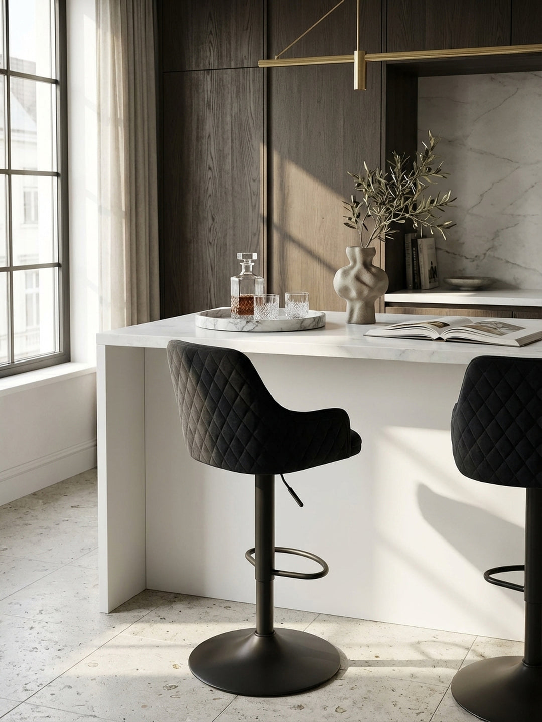 Zwei höhenverstellbare Barhocker aus schwarzem Samt nebeneinander an einer langen Küchentheke, perfekt für gesellige Abende in einem modern-klassischen Interieur._