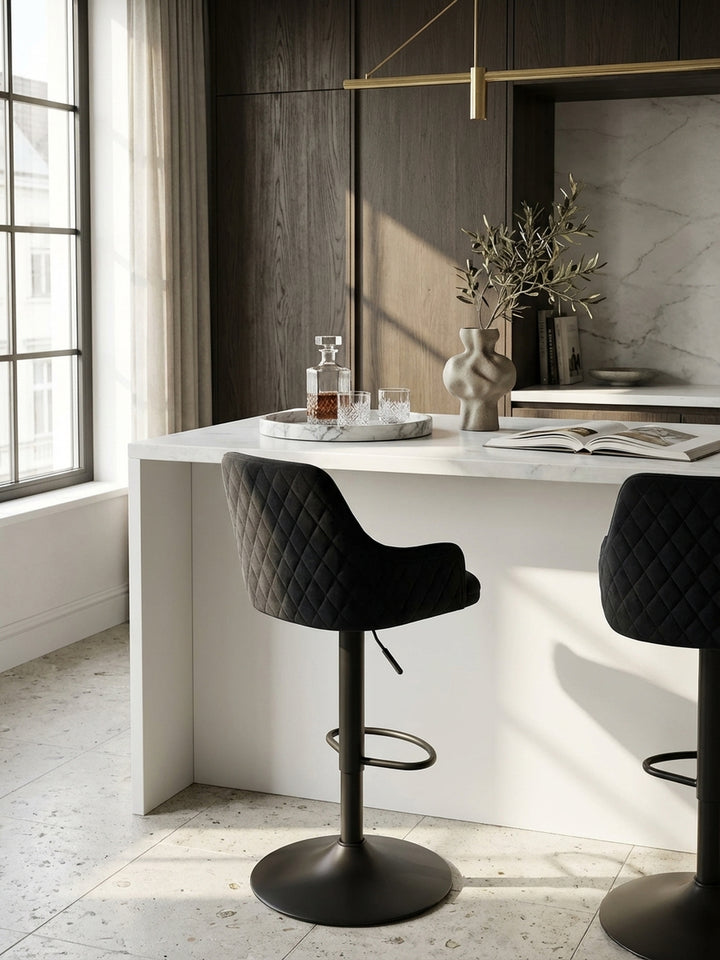 Zwei höhenverstellbare Barhocker aus schwarzem Samt nebeneinander an einer langen Küchentheke, perfekt für gesellige Abende in einem modern-klassischen Interieur._