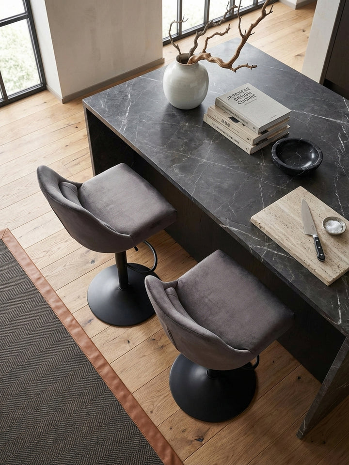Grauer Samt-Küchenhocker mit schwarzem Metallfuß aus der Vogelperspektive, elegant an einem dunklen Frühstückstresen platziert._