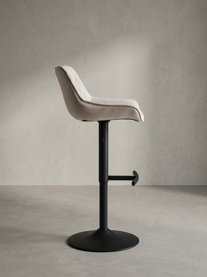 Seitenprofil des schlanken Barhockers aus Samt, das die ergonomische Form der Sitzfläche und die Verstellbarkeit der Sitzhöhe verdeutlicht._