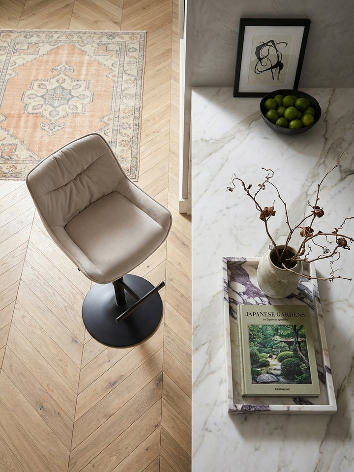 Draufsicht auf den höhenverstellbaren Samt-Barhocker in Beige, der stilvoll an einem grauen Küchentresen in einem modern-klassischen Ambiente platziert ist._