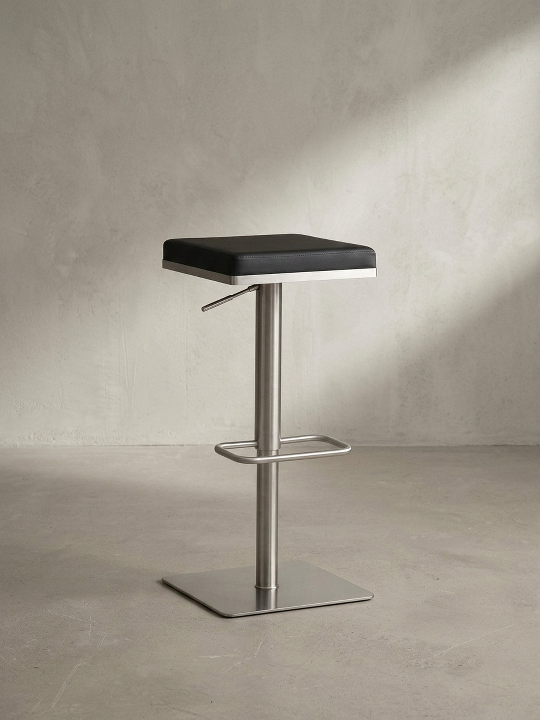 Gesamtansicht des eleganten Tresenhockers, der modernes Design durch die Kombination von schwarzem Kunstleder und gebürstetem Edelstahl verkörpert._