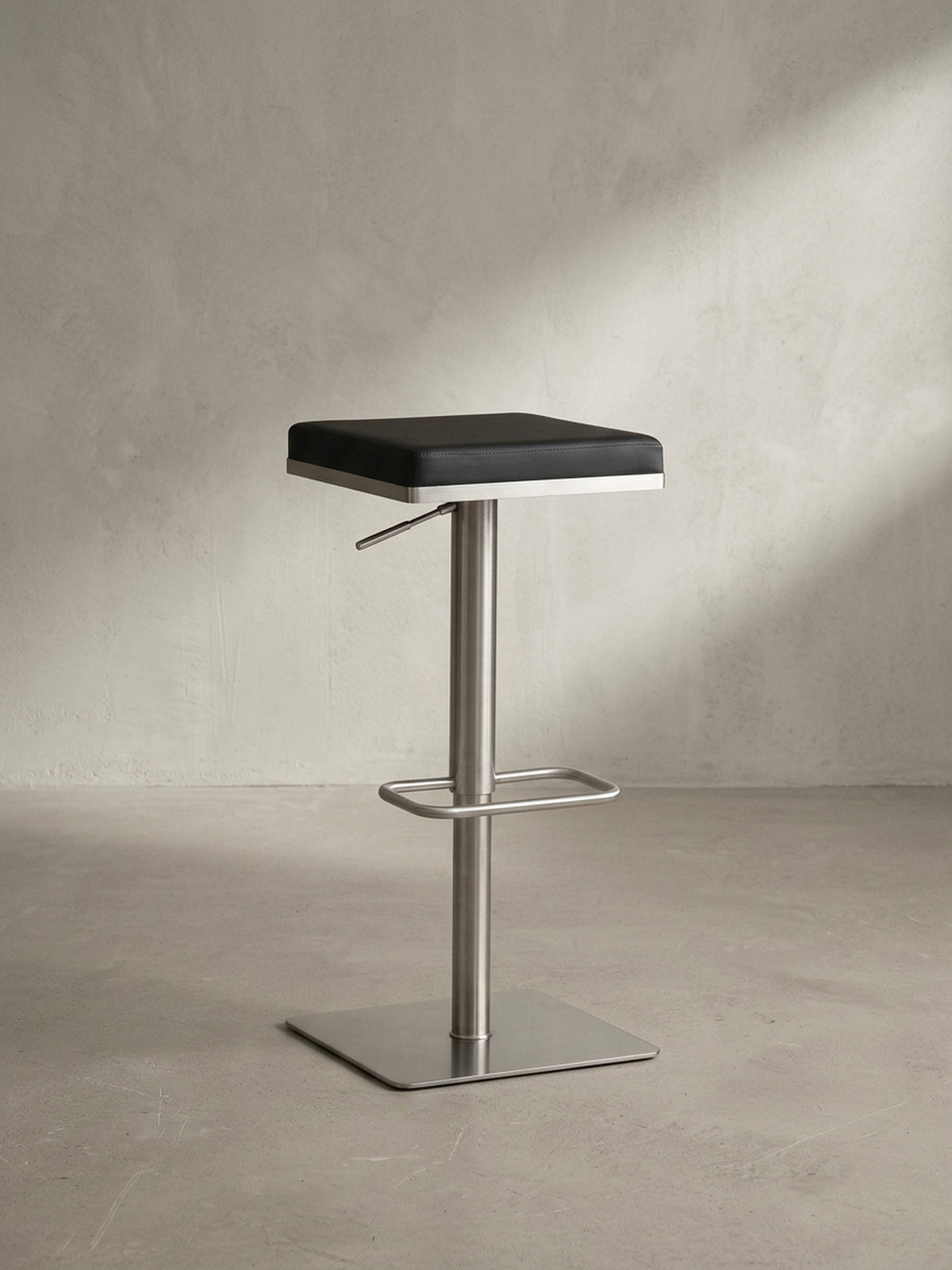 Gesamtansicht des eleganten Tresenhockers, der modernes Design durch die Kombination von schwarzem Kunstleder und gebürstetem Edelstahl verkörpert.
