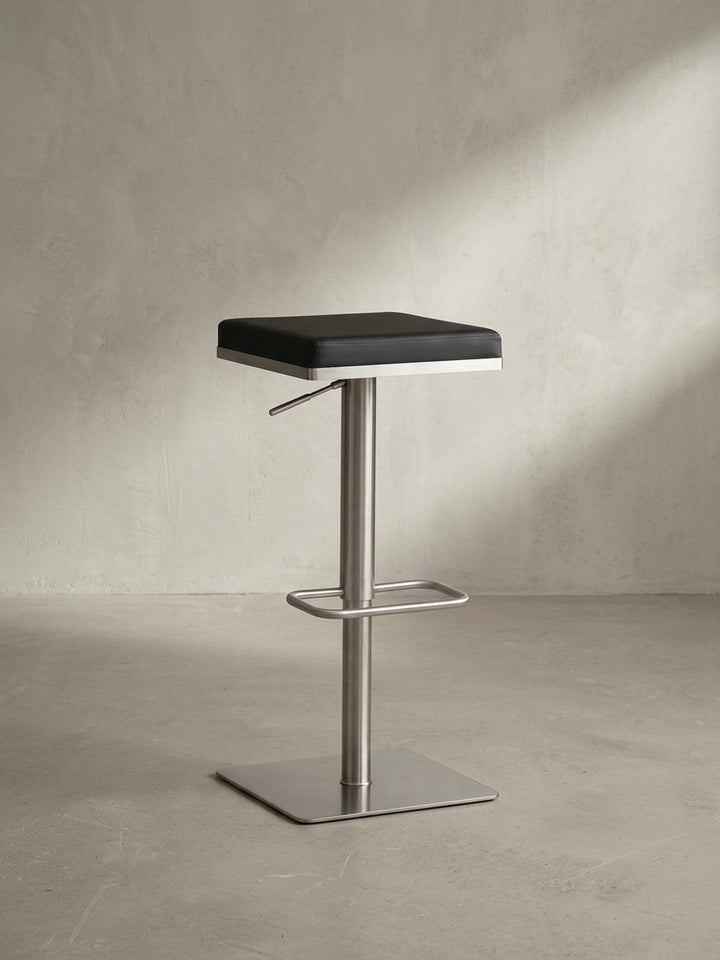 Gesamtansicht des eleganten Tresenhockers, der modernes Design durch die Kombination von schwarzem Kunstleder und gebürstetem Edelstahl verkörpert._