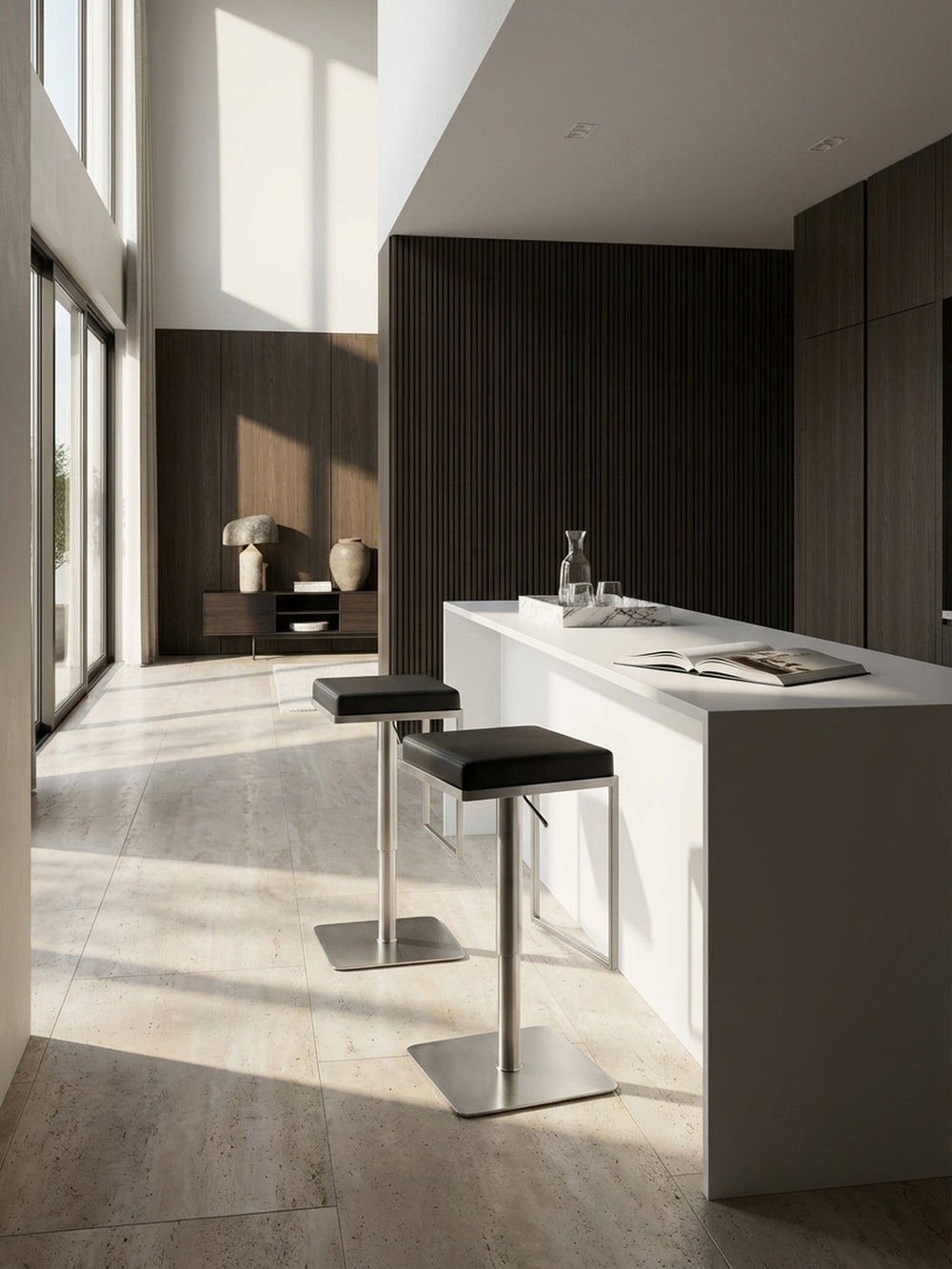Moderner Barhocker aus schwarzem Kunstleder und Edelstahl an einer minimalistischen Kücheninsel aus weißem Corian vor einer dunklen Eichenholzwand._