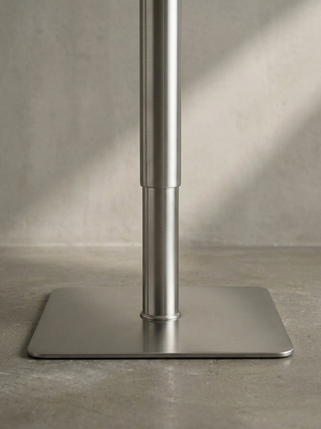 Nahaufnahme des kleinen Hebels zur Höhenverstellung unter der schwarzen Sitzfläche des eleganten Bistrohockers aus Metall._