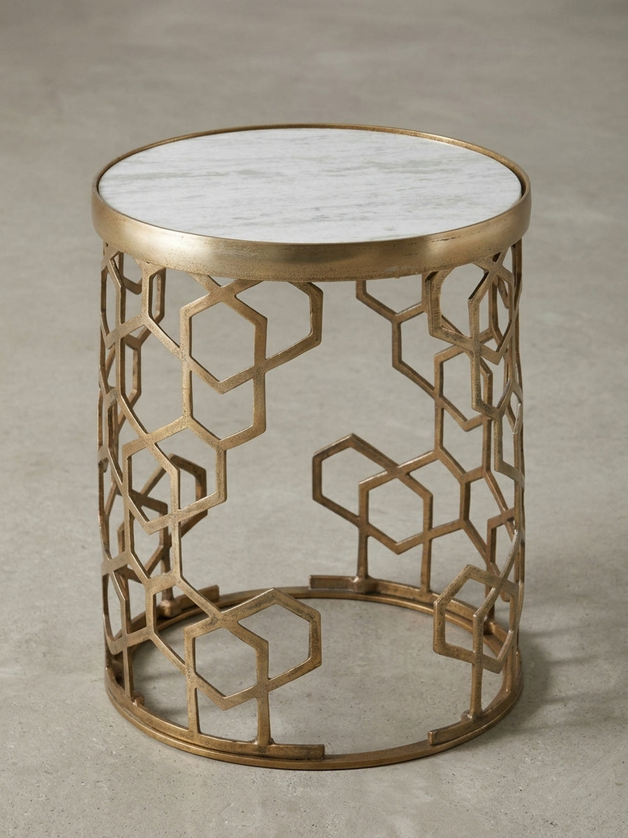 Schräge Perspektive auf den Wohnzimmertisch, die das Zusammenspiel von der massiven Marmorplatte und dem filigranen, goldenen Gittergestell betont._