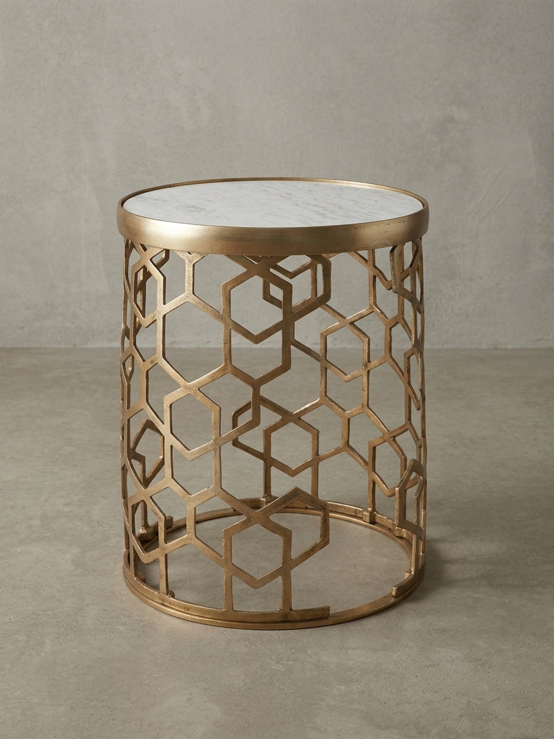 3/4-Ansicht des Sofatisches mit 46 cm Durchmesser, der das kunstvolle, durchbrochene Sechseckmuster des goldfarbenen Aluminiumgestells zur Geltung bringt._