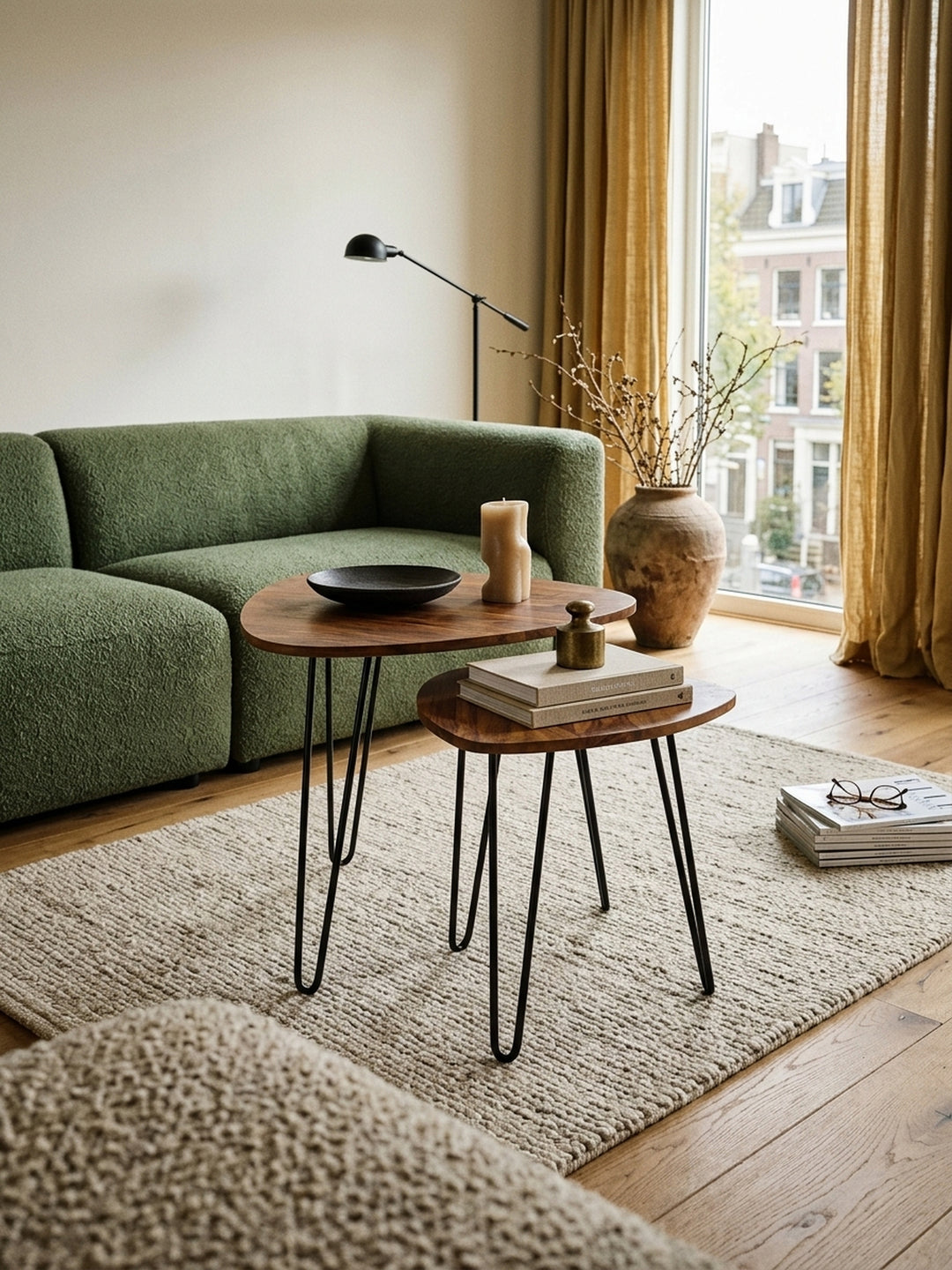 Design Satztisch aus massivem Sheeshamholz im eleganten Wohnzimmer. Das 2er Set Beistelltische mit schwarzen Hairpin-Legs steht auf einem hellen Wollteppich neben einem modernen Sofa._