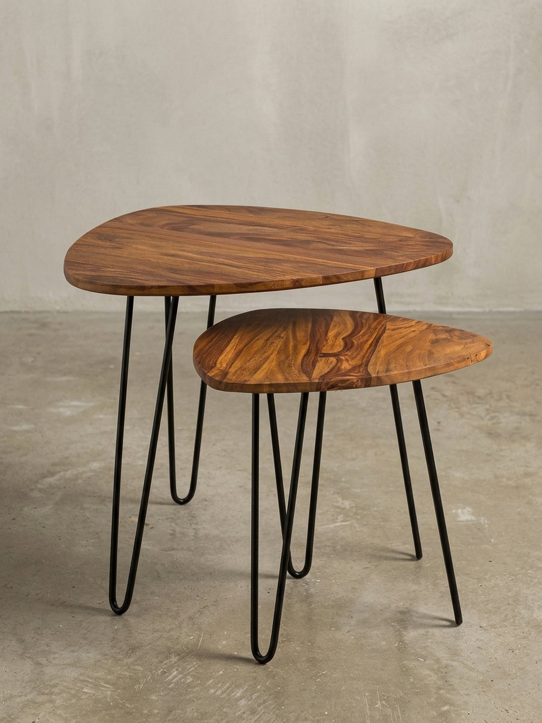 Fokus auf den fließenden Übergang von Holzplatte zu Metallbein. Der Kontrast zwischen dem warmen Massivholz und dem kühlen, schwarzen Eisen macht diesen Designtisch zum Hingucker._